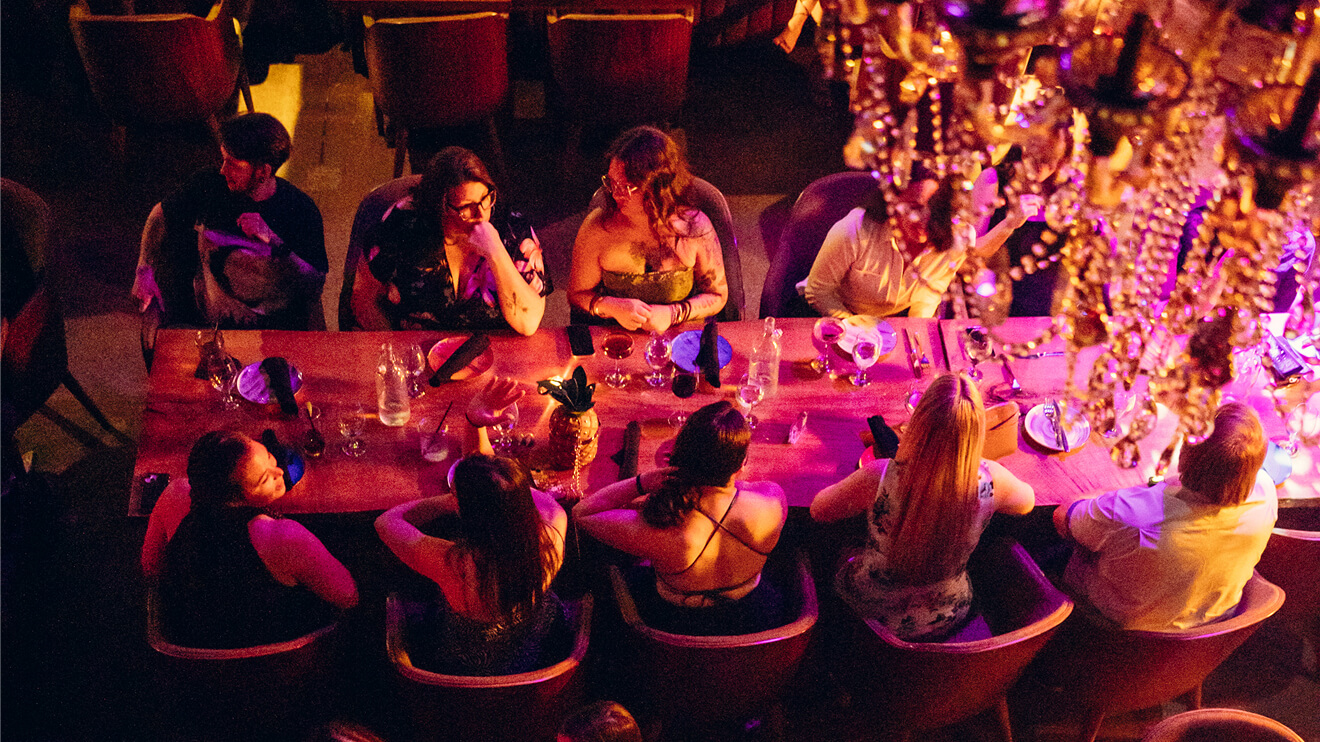 A group sitting around a large dining table at a business dinner party hosted at Fabrika, a top venue for corporate private events in Philadelphia.