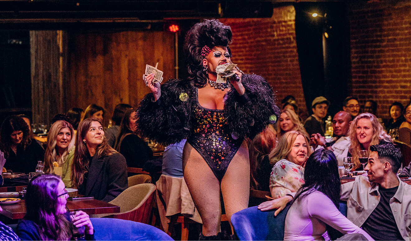 A glamorous drag queen performing live in front of a seated crowd at Fabrika Drag Brunch in Philadelphia.