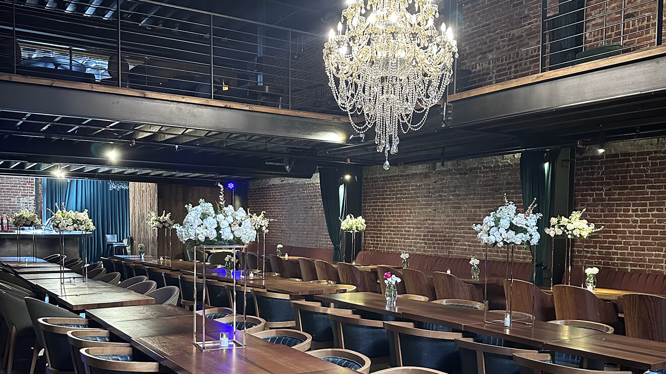 Elegantly set wooden dining tables with white floral arrangements at Fabrika in Philadelphia, highlighting great restaurant ambiance and interior design.